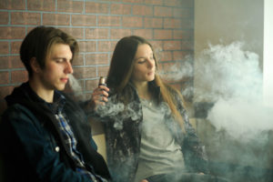 Kids vaping against brick wall