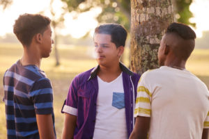 Teenage boys smoking by a tree